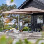 Deck with lounge chairs, umbrellas, and seating area in front of a house with glass doors.