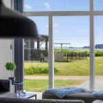 Large window with view of garden and water. Black lamp and sofa in foreground.