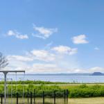 Outdoor area with view of lake and sky. Play equipment and fence are visible.
