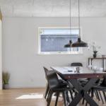 Dining room with table, chairs, and window. Wooden wall and pendant lamps.