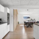 Modern kitchen with dining area and living room in the background.