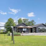 Modern villa with terrace, garden, and swing under blue sky.