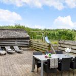 Terrasse mit Tisch, Stühlen, Liegen und Spielplatz. Hinterhof mit Holzzaun und Grünfläche.