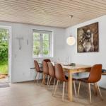 Esszimmer mit Holztisch, braunen Stühlen und Fenster zur grünen Außenterrasse.