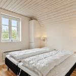 Schlafzimmer mit Doppelbett, Fenster und Holzboden. An der Wand hängen zwei Lampen.