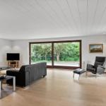 Living room with sofa, armchair, and view of green areas.