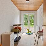 A room with wooden ceiling, window to garden, and childs rocking horse.