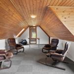 Attic room with four leather chairs and wooden ceiling