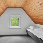 Bedroom with wooden ceiling, window, and bed.