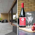 Terrace with seating and green field view. Wine bottle, glasses, and grapes on table.