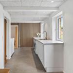 Kitchen with washing machine and window. Wooden wall in background.