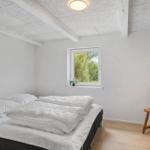 Bedroom with bed, chair, and window. Ceiling with beams.