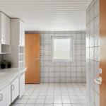 Bathroom with sink, mirror, and window. Tiles on walls and floor.
