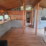 Küche mit Holzdecke, Arbeitsfläche und Einbauküche. Essbereich mit Tisch und Stühlen.