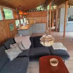 Wohnzimmer mit Sofa, Esstisch und Küche im Holzhaus