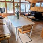 Essbereich mit weißem Tisch, Stühlen und Sofa. Holzwände und Boden.