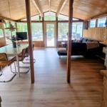 Haus mit Holzdecke, Essbereich und Wohnbereich mit Sofa und Blick auf Garten.