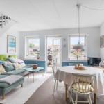 Wohn- und Essbereich mit Sofa, Tisch und Stühlen. Hintergrund: Fenster und Treppe.