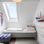 Ein Schlafzimmer mit Dachfenster, Bett, Kissen und Dekoration.
