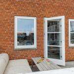 Roter Backsteinbau mit offener Tür und Terrasse mit Sofa und Tisch.