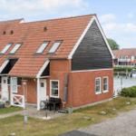 Haus mit rotem Dach und Backsteinfassade an Wasserfront mit Booten.