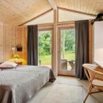 Schlafzimmer mit Holzwand, Bett, Schreibtisch und Blick auf Garten.