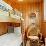 Zimmer mit Doppelstockbett, Stuhl und Holzwandverkleidung.