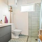 Badezimmer mit Waschbecken, Toilette und Dusche mit Bademattenkorb.