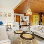 Wohnzimmer mit Sofa, Sesseln und Holzdecke. Gelber Schrank und Kamin sichtbar.