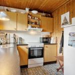 Küche mit Holzwand, Küchenschränken, Herd und Kühlschrank.