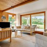 Wohnzimmer mit Holzwand, Sofa, Fernseher und Blick auf die Terrasse.