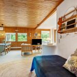 Wohn- und Essbereich mit Holzdecke, Sofa, Tisch und Fenstern.
