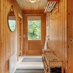 Holzgetäfelte Flur mit Spiegel, Schuhschrank und Tür zum Garten.