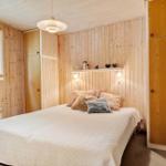 Schlafzimmer mit Holzwand, Bett, Kleiderschrank und Fenster mit Jalousie.