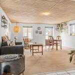 Wohn- und Essbereich mit Holzboden, Decke und Möbeln. Zimmer mit Fenstern und Pflanzen.