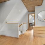 Dachgeschoss mit Holzboden, Treppe und Schrank. Runde Spiegel an der Wand.