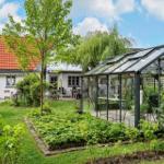 Haus mit Garten, Gewächshaus und Terrasse unter blauem Himmel.