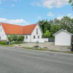 Weiße Villa mit rotem Dach, Garage und Gartenbereich an Straße.