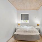Schlafzimmer mit Doppelbett, zwei Nachttischen und einem Fenster mit Jalousie.