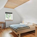 Schlafzimmer mit Dachschräge, Bett, Schreibtisch und Stuhl.