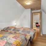 Schlafzimmer mit Bett, Holzdecke und Tür zum angrenzenden Raum.