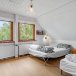 Zwei Betten, Fenster mit Blick auf Bäume, Holzboden, weiße Wände und Decke.