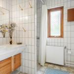 Badezimmer mit Waschbecken, Dusche, Toilette und Fenster.