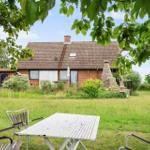 Haus mit Garten, Terrasse und Grillplatz. Blick durch Baumkronen auf das Anwesen.