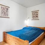 Ein Schlafzimmer mit Holzbett, blauer Bettwäsche, Wandbildern und einem blauen Schrank.