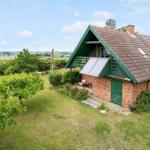 Ein Haus mit grünem Dach und Backsteinfassade auf einer grünen Wiese.
