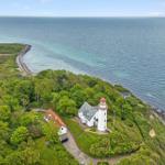 Lichtturm und Haus auf grüner Halbinsel am Meer