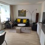 Wohnzimmer mit Sofa, Sitzgelegenheiten und TV. Balkon mit Blick.