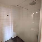 Dusche mit Duschbrause, Glaswand und Fliesenboden.