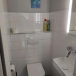 Badezimmer mit Toilette, Waschbecken und Spiegel mit Beleuchtung.